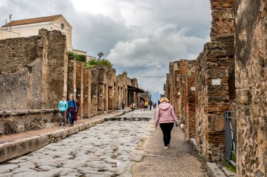 Pompei, İtalya - 5 Kasım 2022: Orijinal taş kaldırımlarını, kaldırımları ve Pompeii 'deki tuğla binaları gösteren antik Roma caddesi manzarası.