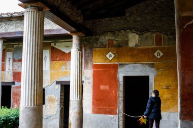 Pompeii, İtalya - 05 Kasım 2022: Bir ziyaretçi Pompeii arkeoloji sahasında lüks bir Roma villasının peristyle üzerindeki yenilenmiş freskleri ve flüt sütunlarını takdir ediyor.