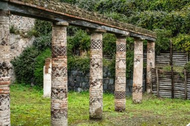 Pompeii, İtalya - 05 Kasım 2022: Pompeii arkeoloji sahasındaki bir avluda pırlanta desenli tuff ustalarının yer aldığı bir sıra antik sütun.