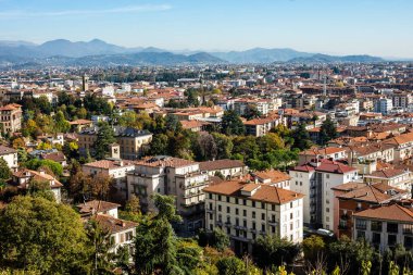 Bergamo, İtalya - 7 Kasım 2022: Venedik Citt Alta Duvarları 'ndan kırmızı kiremitli çatılar, modern daireler ve verimli yeşil ağaçlar (Citta Bassa) manzaralı yüksek açılı panoramik manzara.