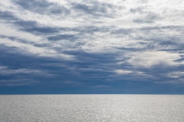 Estonya 'daki Baltık Denizi' nin sakin ufkuna yansıyan ağır mavi bulutlar ile dramatik bulutlu gökyüzünün geniş açılı görüntüsü