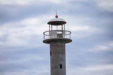 Saaremaa, Estonya 'da terk edilmiş Kiipsaare deniz fenerinin en üst galerisi ve fener odasının karamsar bir gökyüzünün altında detaylı bir görüntüsü.