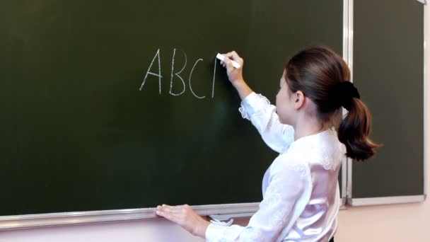 Schoolgirl writing letters on the blackboard — Stock Video