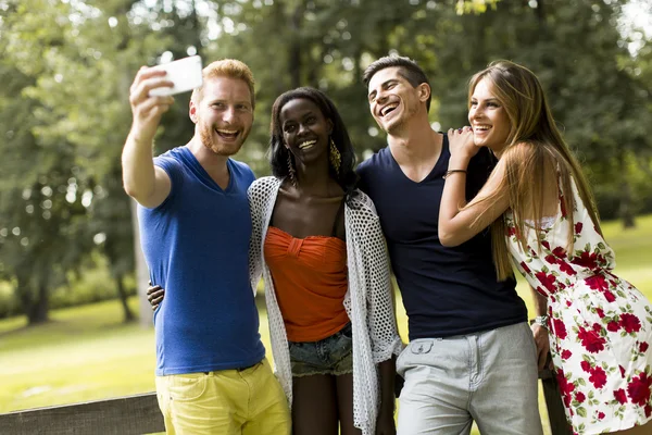 Młodzi przyjaciele wielorasowe biorąc selfie w parku — Zdjęcie stockowe