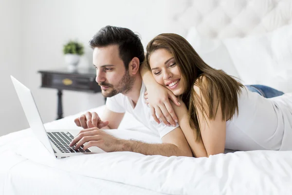 Casal com laptop na cama — Fotografia de Stock