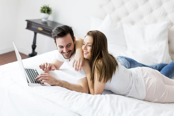 Casal com laptop na cama — Fotografia de Stock