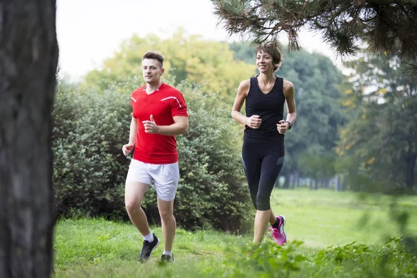 Giovane coppia che corre nel parco — Foto Stock