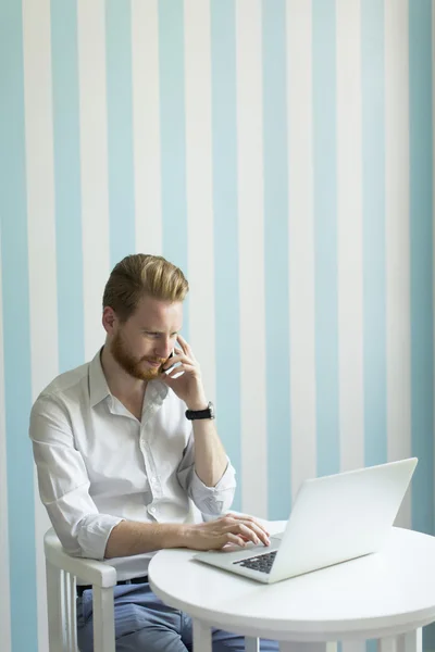 Man med en bärbar dator och en telefon — Stockfoto