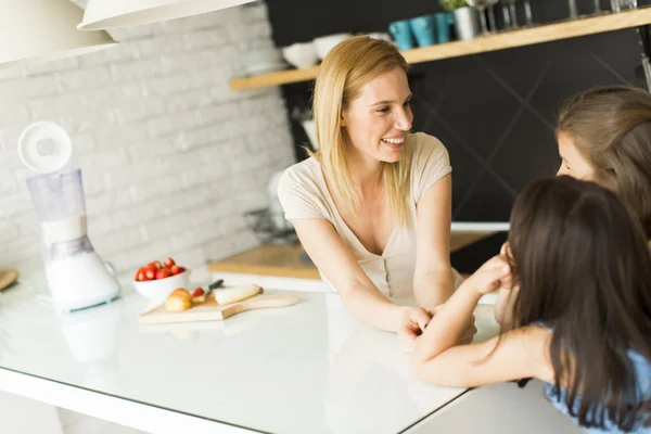 Vrouw en twee meisjes in de keuken — Stockfoto