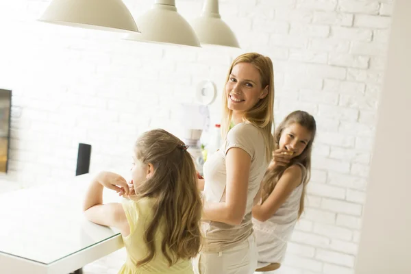 Vrouw en twee meisjes in de keuken — Stockfoto