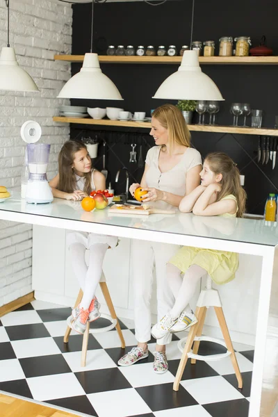 Mulher e duas meninas na cozinha — Fotografia de Stock