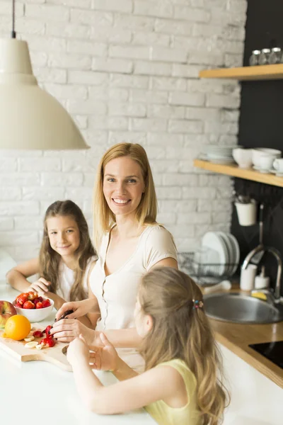 Frau und zwei Mädchen in der Küche — Stockfoto