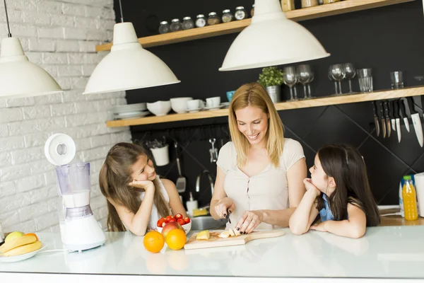 Žena a dvě dívky v kuchyni — Stock fotografie