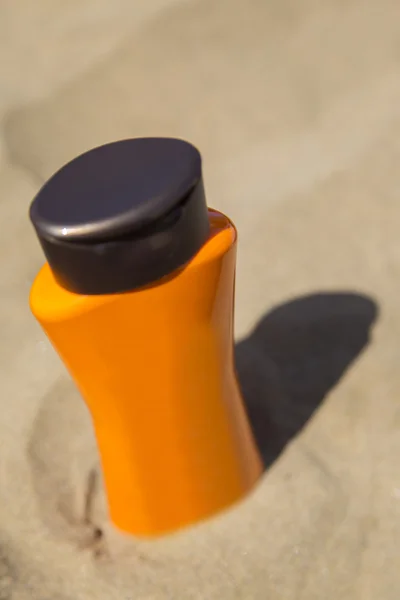 Butelki z filtrem przeciwsłonecznym w piasku — Zdjęcie stockowe