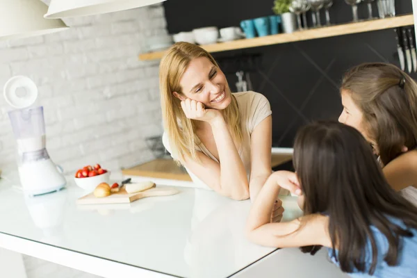 Vrouw en twee meisjes in de keuken — Stockfoto