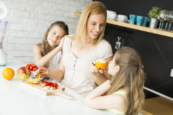 Mulher e duas meninas na cozinha — Fotografia de Stock