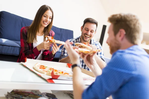 Young people eating pizza in the room — Stock Photo, Image