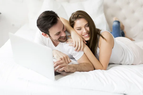 Jovem casal com laptop na cama — Fotografia de Stock