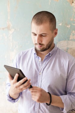 Duvar tarafından tablet ile genç adam