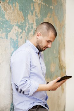 Duvar tarafından tablet ile genç adam