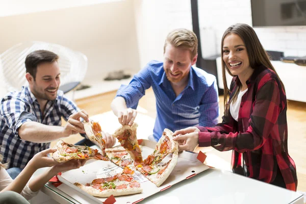 Молодые люди едят пиццу в комнате — стоковое фото