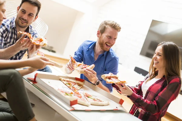 Друзья едят пиццу в комнате — стоковое фото