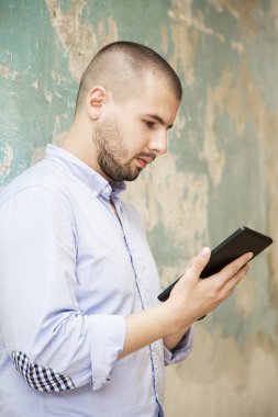 Duvar tarafından tablet ile genç adam