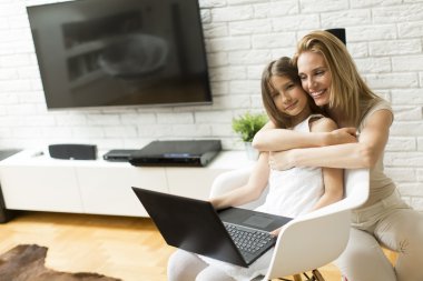 Anne ve kızı dizüstü bilgisayarla çalışıyor.