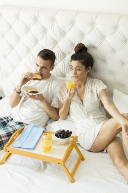 Yatakta kahvaltı yapan çift.