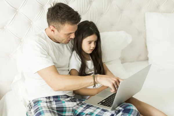 Padre e figlia con computer portatile a letto — Foto Stock