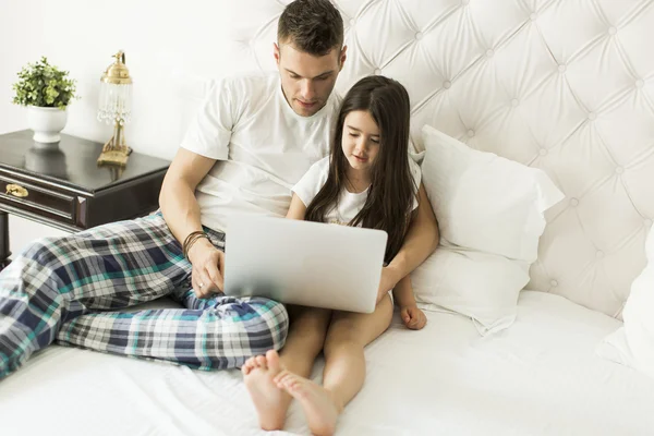 Padre e figlia con computer portatile a letto — Foto Stock