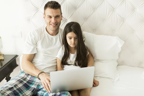 Padre e hija con portátil en la cama — Foto de Stock