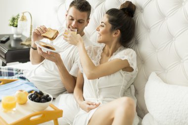 Yatakta kahvaltı yapan çift.