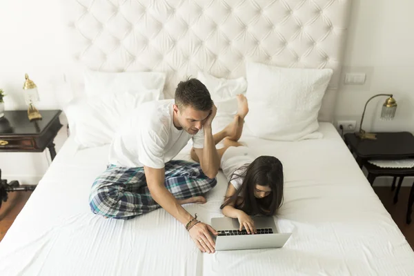 Padre e figlia con computer portatile a letto — Foto Stock