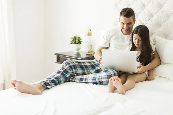 Padre e figlia con computer portatile a letto — Foto Stock