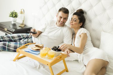 Yatakta kahvaltı yapan çift.