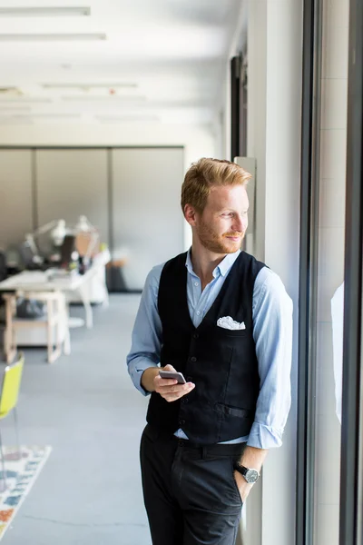 Young man with mobile phone in the office — Stock Photo, Image