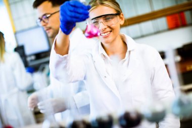 Biyokimya laboratuvarında sıvıyı inceleyen genç ve güzel bir kadın bilim adamı.