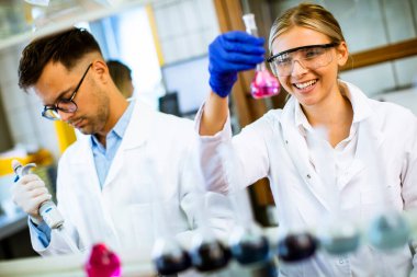 Biyokimya laboratuvarında sıvıyı inceleyen genç ve güzel bir kadın bilim adamı.