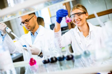 Biyokimya laboratuvarında sıvıyı inceleyen genç ve güzel bir kadın bilim adamı.