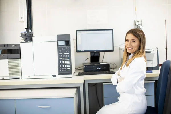 Jonge Vrouwelijke Wetenschapper Witte Labjas Zittend Bij Gaschromatografieapparatuur Het Biomedisch — Stockfoto