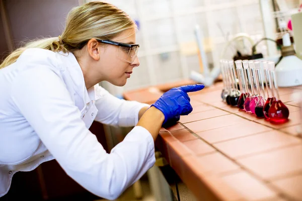 液体サンプルを分析する白衣の若い女性科学者生物医学研究所 — ストック写真