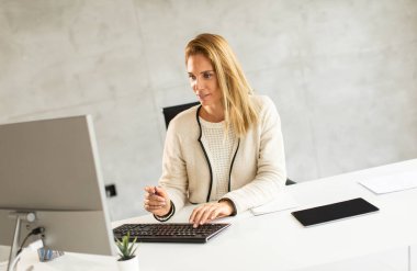 Parlak modern ofiste dizüstü bilgisayarla çalışan güzel bir iş kadını.