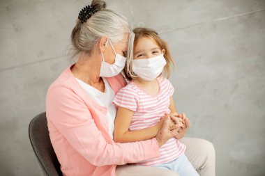 Büyük anne ve küçük tatlı torun solunum maskesi takıyor.