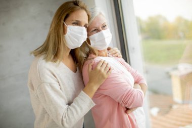 Coronavirus 'tan korunmak için evde tıbbi maskeler takan yaşlı bir kadın var.
