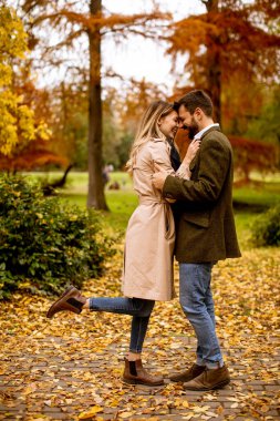 Güz parkında yürüyen yakışıklı genç çift.