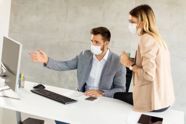 Genç iş adamları ofiste sağlıklarını korumak ve korumak için maske takarlar.