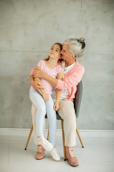 Little Girl Her Grandmother Sitting Chair Grey Wall — Stock Photo, Image