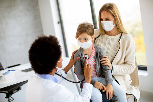 Мать с дочкой на обследовании у педиатра африканской американки