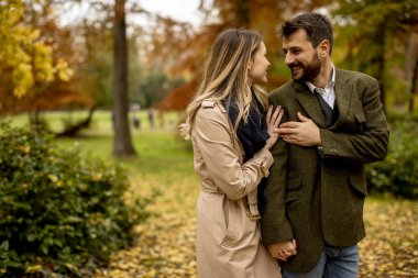 Güz parkında yürüyen yakışıklı genç çift.